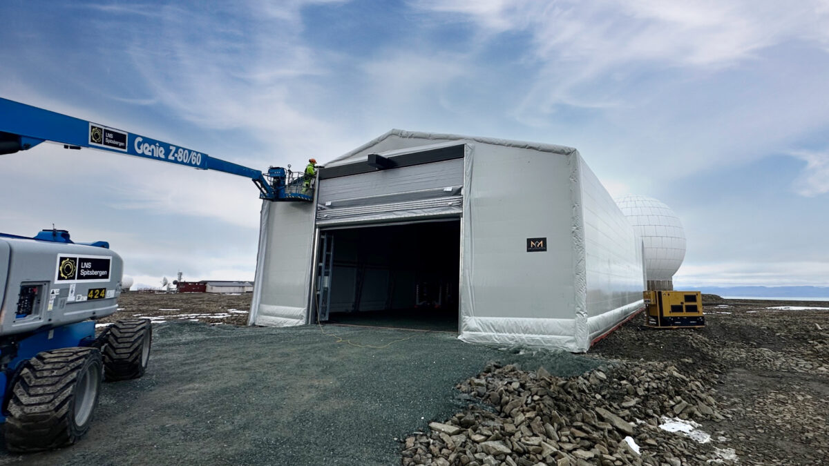 En arbeidsplattform brukes for å vedlikeholde en stor isolert talthall fra Hallgruppen på en gruslagt plass.