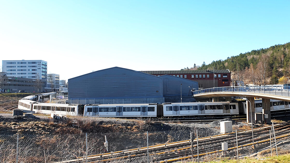 En isolert talthall med flere porter, bygget av Hallgruppen, ligger nær en jernbane og bro.